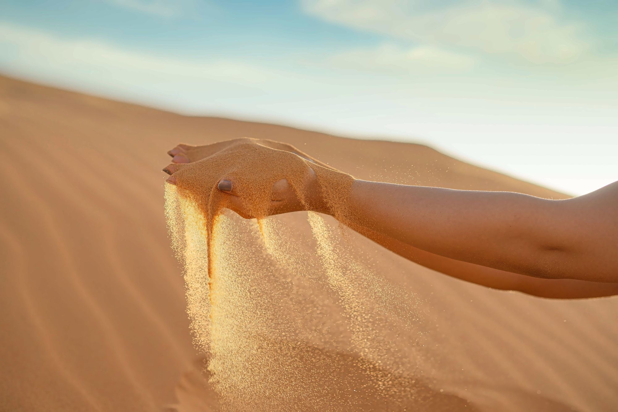 Golden Sahara sand poured through hands on the dunes near Merzouga