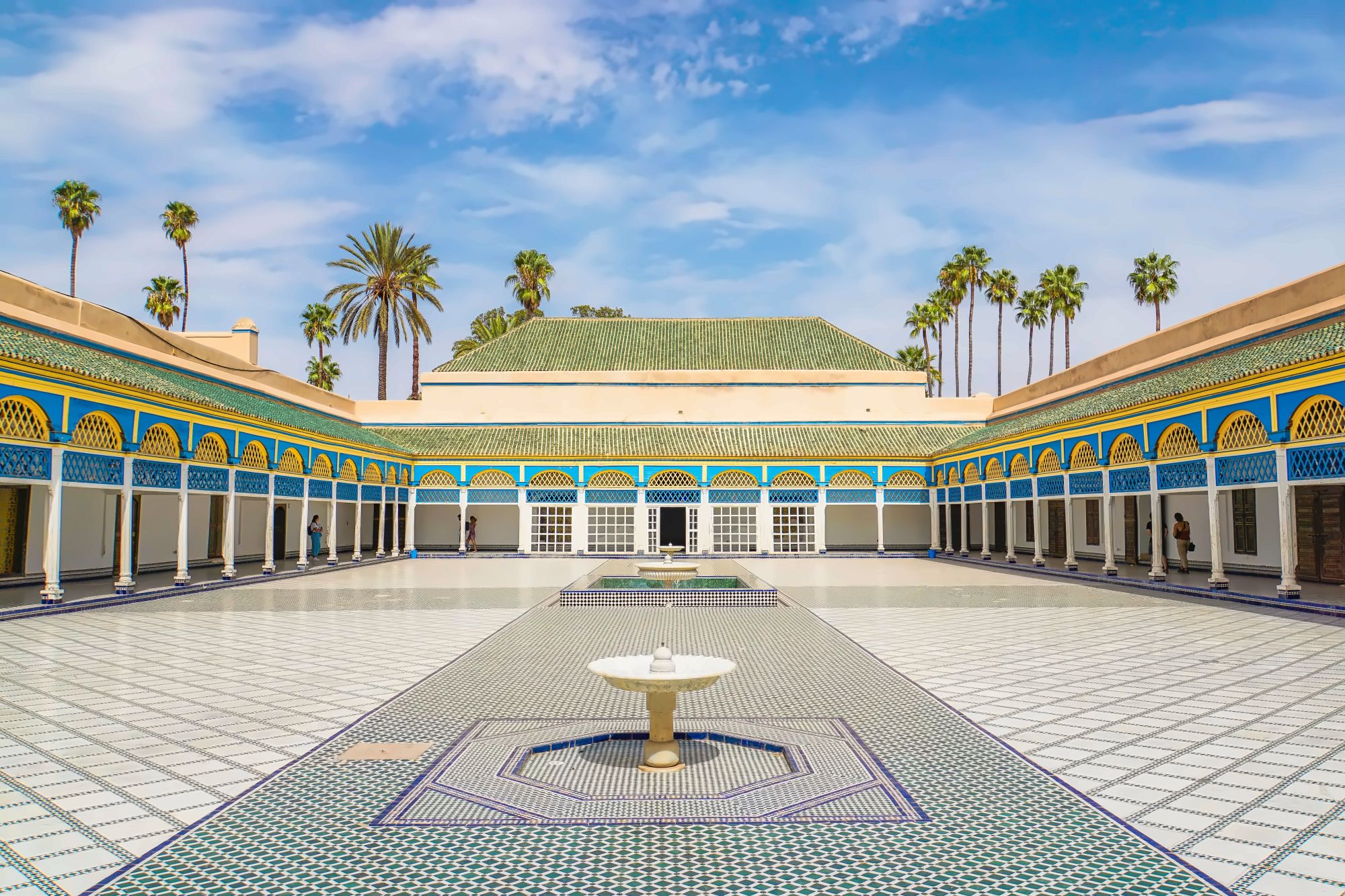 Carved cedar ceiling and zellij tilework above a marble courtyard at the Bahia Palace