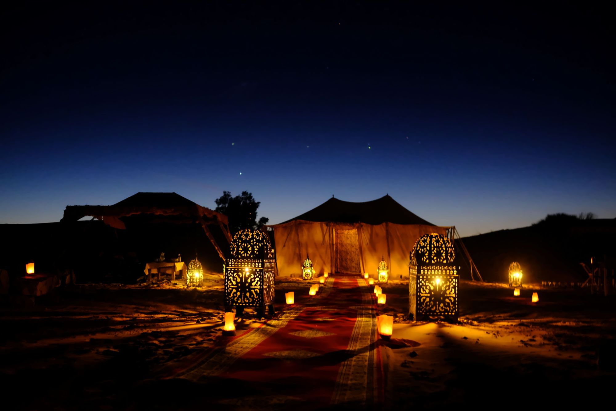 Berber desert camp tents lit against the dunes after dark at Erg Chebbi