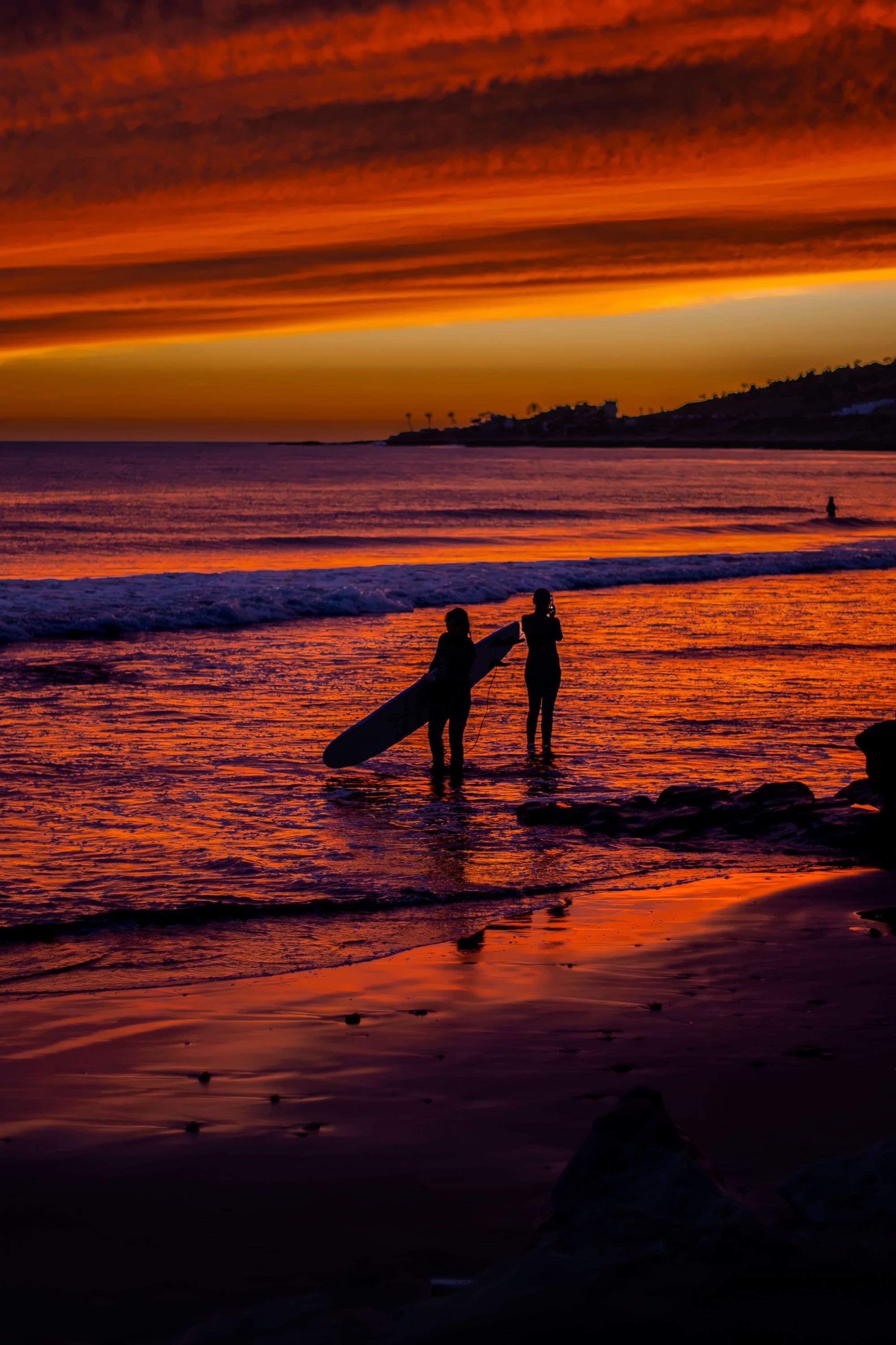 Surfers paddling out at a Taghazout beach break in late afternoon light